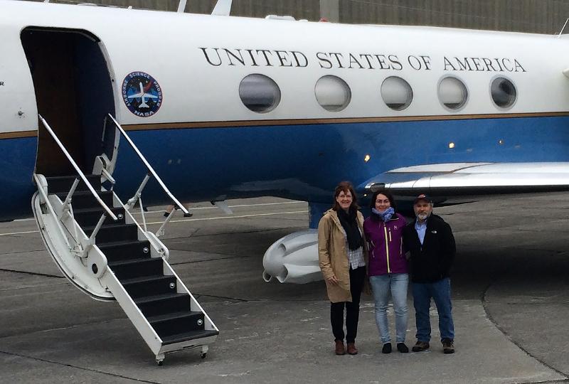 Tre menneske foran eit lite jetfly. På flyet står det United States of America.